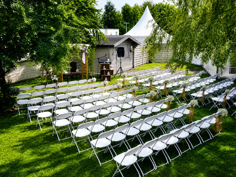 Cérémonie de mariage en extérieur avec rangées de chaises blanches Pack Event et arche fleurie en Loire-Atlantique